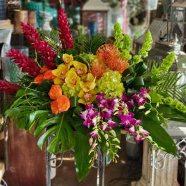 Tropical floral arrangement with orchids, orange roses, and red and green spikes