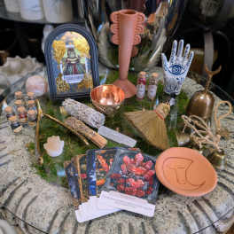 Assorted tarot and ritual items arranged on a glass table