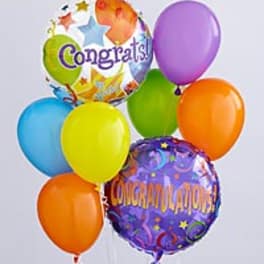 Colorful congratulatory balloons, including two printed foil balloons and several latex balloons