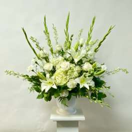 White floral arrangement in a white urn vase