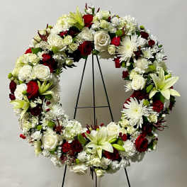 Large floral wreath with white and red flowers on a black stand