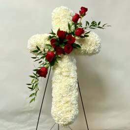 White floral cross with red roses on a stand
