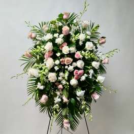 Standing floral spray with pink and white roses on a tripod easel