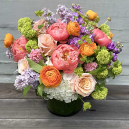 Mixed bouquet of pink, orange, purple, and white flowers in a dark vase