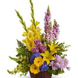Mixed bouquet in a wicker basket with yellow, purple, and blue flowers