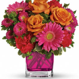 Bouquet of orange roses and pink daisies in a magenta glass vase