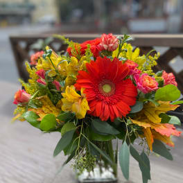 Bouquet of red gerbera daisies and yellow flowers in a glass vase