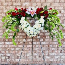 Standing floral wreath with red and white flowers on a metal easel