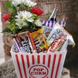 Popcorn bucket gift with candy bars and a small flower bouquet