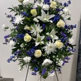 Standing floral spray with white and blue flowers on a metal easel