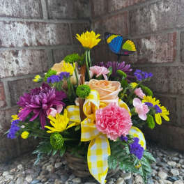 Basket arrangement of colorful flowers with a yellow ribbon and butterfly pick