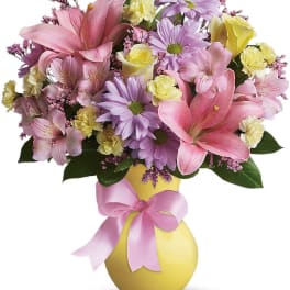 Pink and lavender mixed bouquet in a yellow vase with a pink ribbon