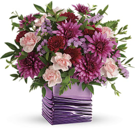 Pink and purple mixed flower arrangement in a purple glass vase