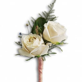 Two white rose boutonnieres with greenery and jeweled pins