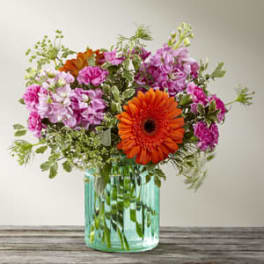 Pink and orange flowers in a turquoise glass vase