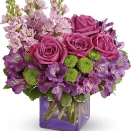 Purple roses and alstroemeria in a square glass vase