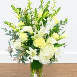 White and pale yellow floral arrangement in a glass vase