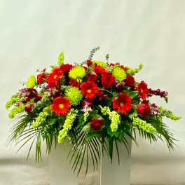 Large red and neon green floral arrangement in a white container