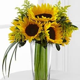 Sunflower arrangement in a tall clear glass vase