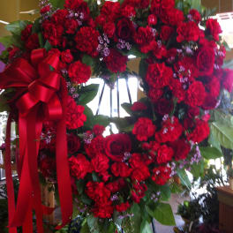 Heart-shaped red floral wreath with a large red ribbon bow