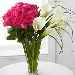 Pink roses and white calla lilies in a clear glass vase