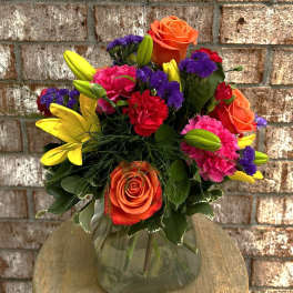 Colorful bouquet of roses, lilies, and carnations in a glass vase