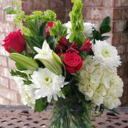 Bouquet of red roses, white lilies, and white chrysanthemums in a glass vase