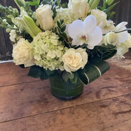 White roses and orchids arranged in a green vase