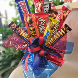 Assorted chocolate candy bars wrapped in colorful cellophane with a ribbon bow