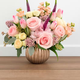 Pink and cream flower arrangement in a ribbed gold vase