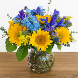 Yellow sunflowers and blue flowers in a glass vase