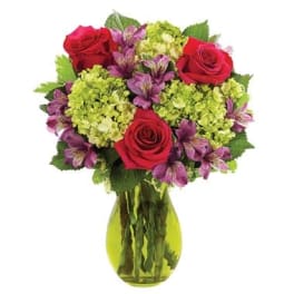 Bouquet of red roses and purple flowers in a green glass vase