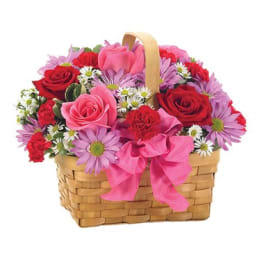 Basket of pink and red flowers with a pink ribbon bow