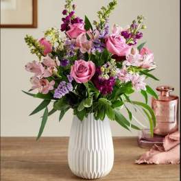 Pink roses and purple flowers in a white vase