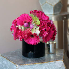 Bright pink gerbera daisies and mixed blooms in a black vase
