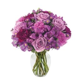 Purple bouquet of roses and mixed flowers in a clear glass vase