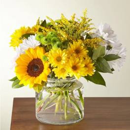 Bouquet of sunflowers, white daisies, and yellow flowers in a glass vase