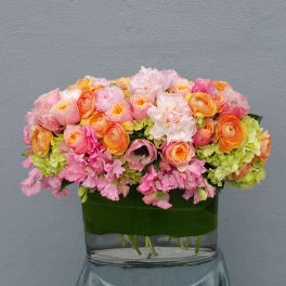 Pink and peach flowers arranged in a low glass vase