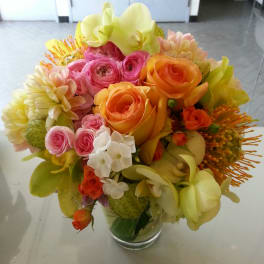 Bouquet of pink, orange, and yellow flowers in a clear glass vase
