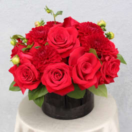 Red roses and red mums arranged in a black round box