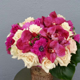 Pink and cream bouquet with roses and orchids in a gold vase