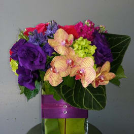 Colorful bouquet with orchids and purple flowers in a glass vase