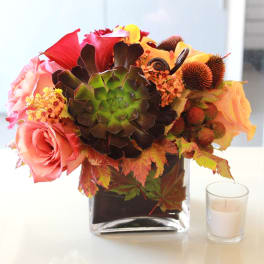 Mixed bouquet with roses, calla lilies, and a succulent in a glass vase