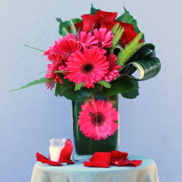 Pink gerbera daisies and red roses in a tall glass vase