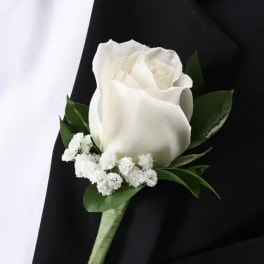 White rose boutonniere with small white filler flowers on a black suit lapel