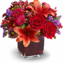 Red roses and orange lilies in a square glass vase