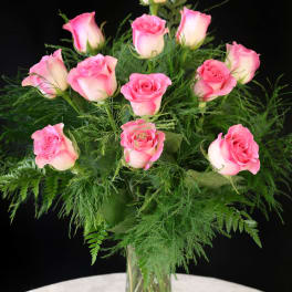 Pink roses arranged in a clear glass vase with airy greenery
