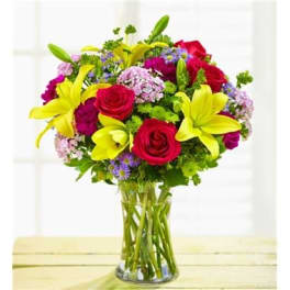 Bouquet of red roses and yellow lilies in a clear glass vase