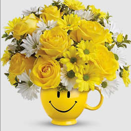 Yellow roses and white daisies in a smiley-face mug