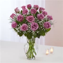 Pink roses arranged in a clear glass vase with baby's breath